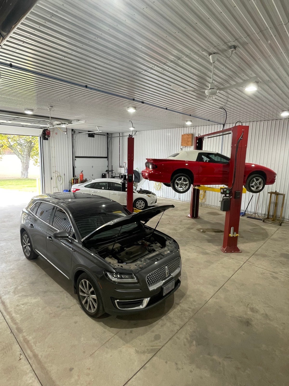 SUV with hood open in front of a car on a lift